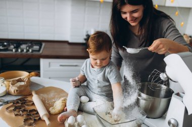 Mutfakta mutlu bir aile. Anne ve oğul hamuru hazırlıyorlar, kurabiye pişiriyorlar.
