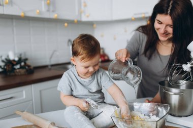Mutfakta mutlu bir aile. Anne ve oğul hamuru hazırlıyorlar, kurabiye pişiriyorlar.
