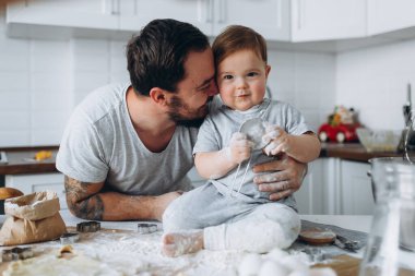 Mutfakta mutlu bir aile. Baba ve oğul hamuru hazırlıyorlar, kurabiye pişiriyorlar.