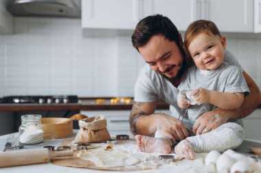 Mutfakta mutlu bir aile. Baba ve oğul hamuru hazırlıyorlar, kurabiye pişiriyorlar.