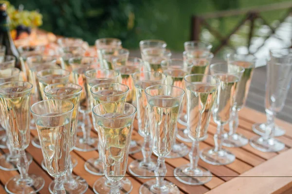 a row of glasses filled with champagne are lined up ready to be served.