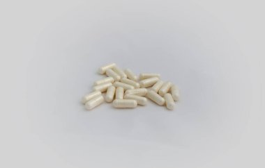 Beyaz arka planda bir sürü hap. Seçici odaklanma. Açık sarı kapsüller beyaz arka plana saçılmış. Virüs tedavisi.