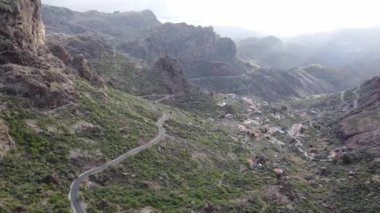 Roque Nublo yakınlarındaki bir vadide, yılanlı yol, küçük köyler ve ağaçlar da dahil olmak üzere uzaktan kumandalı hava aracı. Büyük Kanarya, İspanya