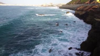 Okyanus güzel güneşli bir günde kayaların arasından geçiyor.