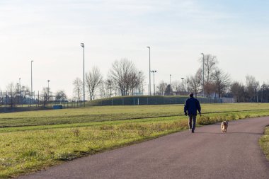 Güney Almanya 'da güneşli bir öğleden sonra köpeğiyle gezen bir adam.