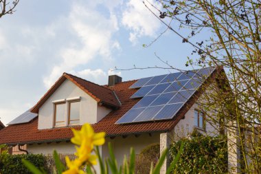 Güney Almanya 'da ilkbahar güneşli bir günde güneş panelleri ve sarı çiçekli çatı.