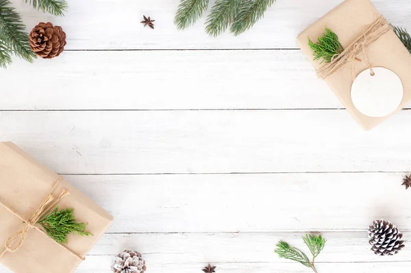 Christmas fir leaves, pine cones and gift  on white rustic wooden background.