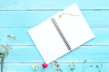 Boş defter ve mavi ahşap arka plan üzerinde kır çiçekleri buketi. Kavram çiçekler Bahar, yaratıcı düz yatıyordu, üstten görünüm tasarımı ile kopya alanı