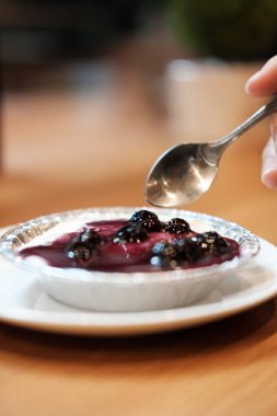 Yapay çiçek kokulu ahşap masa üzerinde yaban mersini peynir kek üzerine el 