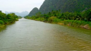 Yüksek dik karstik Dağları'nın eteklerinde geniş sığ nehir manzarası