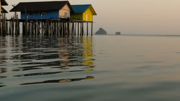 Будинки рибалок піднімаються над краєм води на заході сонця — стокове відео