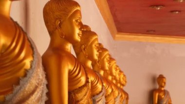 Bir sırada oturan altın Buda heykelleri.