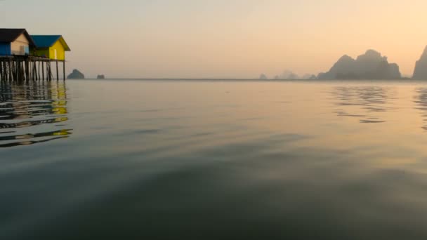 Fischerhäuser ragen bei Sonnenuntergang über die Wasserkante — Stockvideo