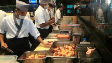 BANGKOK, THAILAND - 26 ARALIK, 2017: Siam Paragon 'daki Japon restoranında şefler. Beyaz üniformalı Asyalı adamlar profesyonel bir mutfakta deniz ürünleri kesiyor..