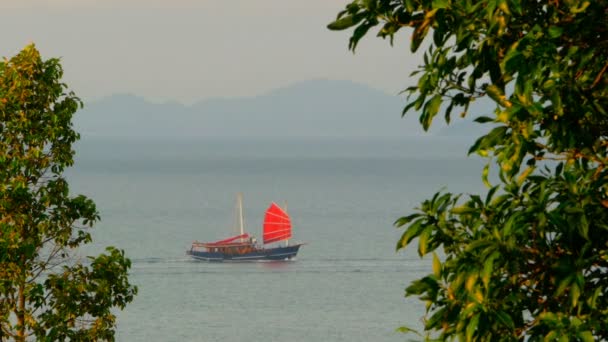 Un barco chino tradicional con velas rojas flota a lo largo del mar al atardecer — Vídeos de Stock