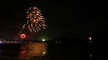 Deniz yüzeyi yukarıda gece gökyüzünde parlak altın havai fişek patlayabilir