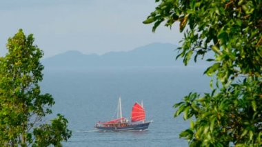 Kırmızı olan geleneksel bir Çin gemi yüzen deniz kenarında günbatımında yelken