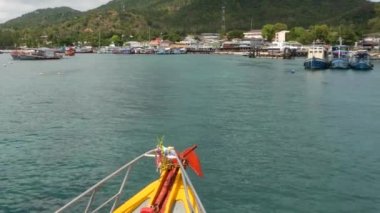 Tılsımlı bir balıkçı teknesi limana giriyor. Tayland 'daki Ko Tao Cennet Adası' ndaki dalış tesisinin limanına doğru yüzen Thai dini tılsımlı parlak bir tekne..