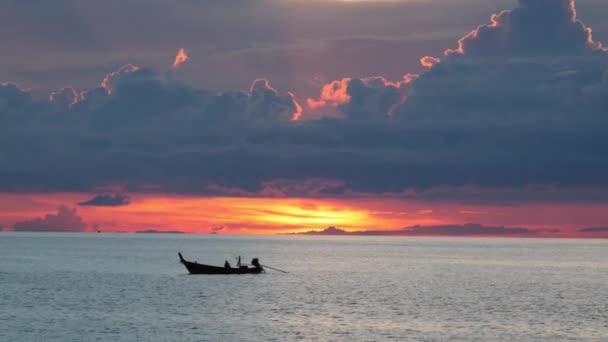 Barco en el mar al atardecer. Silueta de pequeño bote de remos flotando en el agua ondulante de mar tranquilo durante el atardecer en la noche nublada. Paraíso tropical romántico fondo natural. — Vídeos de Stock