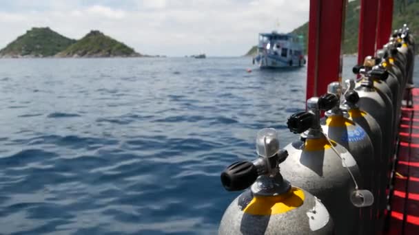 Fila de tanques de oxígeno y equipo de buceo colocado en barco moderno en el océano ondulante cerca de Koh Tao resort, Tailandia. Concepto de deportes turísticos de entretenimiento extremo, aventura y nueva experiencia. — Vídeos de Stock