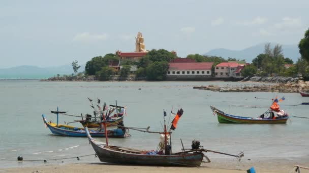 タイのサムイ島の楽園熱帯エキゾチックな島の海辺にある穏やかな水と古いイスラム教徒の釣りのロングテールボートに囲まれた大きな仏寺。文化と宗教の平和共存. — ストック動画