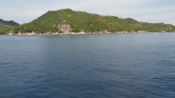 Спокійна вода біля зеленого екзотичного райського острова. Затихла морська вода біля пірнаючого курорту на горбистому зеленому острові Тао в похмурий день у Таїланді. Вид з човна.. — стокове відео