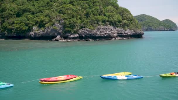 Ilhas no oceano em Ang Thong National Marine Park perto turístico Samui paraíso resort tropical. Mar azul-esverdeado idílico fundo natural com espaço de cópia. Caiaques e canoas esportivas coloridas — Vídeo de Stock