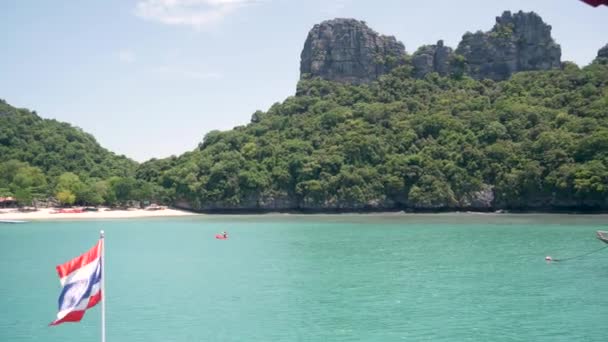 Grupa wysp w oceanie w Ang Thong National Marine Park. Archipelag w Zatoce Tajlandzkiej. Idylliczny turkusowy morze naturalne tło z kopia przestrzeń. Flaga jako symbol narodowy na łodzi. — Wideo stockowe