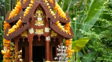 Tahta minyatür koruyucu aile evi. Küçük Budist tapınağı, renkli çiçek çelenkleri. San phra phum servet getirmek için dikildi. Geleneksel saygı hayvani ritüeller, dua törenleri