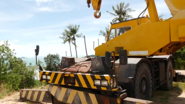 Macchine edili che lavorano nella foresta tropicale. Vista laterale della gru gialla che abbatte alberi esotici nei tropici. Disturbi degli ecosistemi e deforestazione . — Video Stock