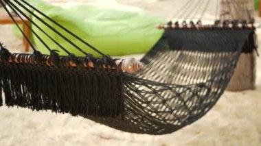 Hindistan cevizi palmiyeleri arasında uzanan siyah hamak. Tropik adanın kumlu cennetine uzanan kenarlarında püsküllü eski tip hipster hamağı. Rahatlayın, seyahat tatil beldesi konsepti.