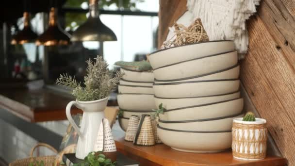Set med porslin i enkla rustika retro kök. Högen med skålar och kanna med vilda blommor på bakgrunden av mysigt kök. Uppsättning vaser och keramiska figurer i vintage stil. Modern snygg bakgrund. — Stockvideo