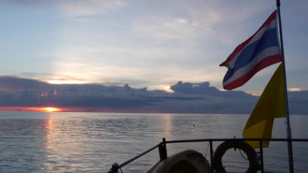 Barco flotando con banderas en la noche. Banderas tailandesas y del rey de Tailandia contra el cielo nublado del anochecer y el mar romántico — Vídeo de stock