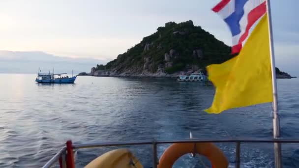 Човен плаває біля тайських прапорів увечері. Силует анонімних осіб, що плавають на човні на хвилястому морі біля Тайської імперії і прапорів Таїланду проти хмарного сонячного неба.. — стокове відео