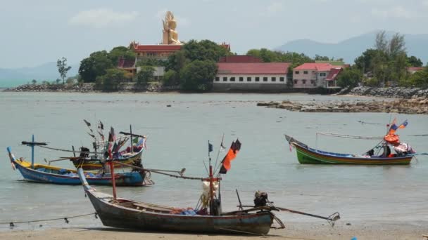 Grote Boeddha tempel omgeven door rustig water en oude moslim vissen longtail boten aan de kust van Samui paradijs tropische exotische eiland, Thailand. Vreedzame coëxistentie van culturen en religies. — Stockvideo