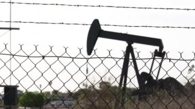 Endüstriyel şehir manzarası. La Brea Inglewood, Los Angeles 'ta. Çitin arkasında Jack 'i pompala. Sondaj kulesi ham petrol çıkarıyor. Çalışan pistonlu bir yağ makinası. Petrol ve doğalgaz endüstrisi
