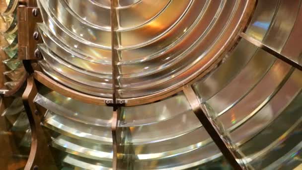 Fresnel lens with brass structure, nautical lighthouse tower. Detail of the glass lantern with rainbow spectrum. System of lamps and lenses to serve as a navigational aid. Old sea searchlight beacon. — Stock Video