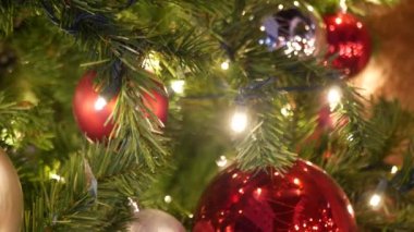 Neşeli Açık Hava Noel Ağacı 'nın yakın çekimleri. Peri arka planında parlak kırmızı toplar var. Odaklanmamış çelenk ışıkları, Bokeh etkisi. Mutlu Noeller ve Mutlu Noeller konsepti.