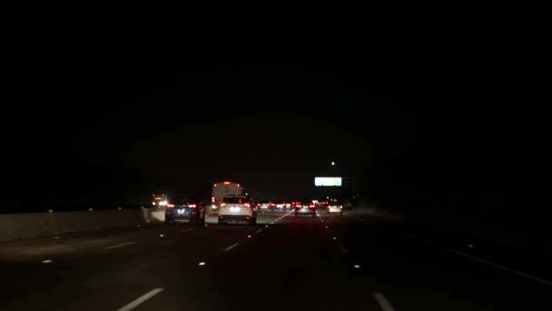 Widok z samochodu. Los Angeles jest zajęte autostradą w nocy. Massive Interstate Highway Road w Kalifornii, USA. Automatyczna jazda po drogach ekspresowych. Koncepcja korków i transportu miejskiego. — Wideo stockowe
