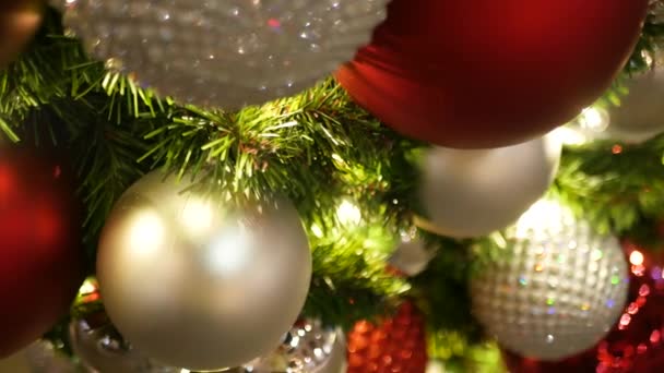 Крупный план празднично украшенной наружной елки с ярко-красными шариками на размытом блестящем фоне феи. Обезжиренные гирлянды, эффект Боке. Концепция "С Рождеством и счастливыми праздниками". — стоковое видео