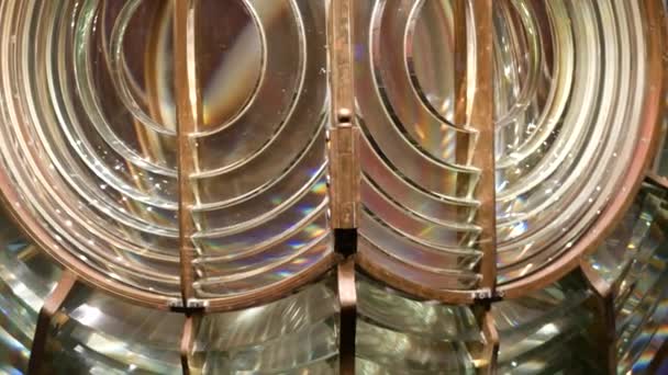 Fresnel lens with brass structure, nautical lighthouse tower. Detail of the glass lantern with rainbow spectrum. System of lamps and lenses to serve as a navigational aid. Old sea searchlight beacon. — Stock Video