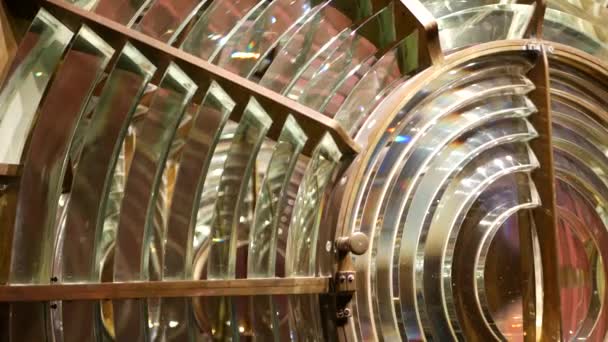 Fresnel lens with brass structure, nautical lighthouse tower. Detail of the glass lantern with rainbow spectrum. System of lamps and lenses to serve as a navigational aid. Old sea searchlight beacon. — Stock Video