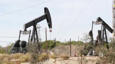 Endüstriyel şehir manzarası. La Brea Inglewood, Los Angeles 'ta. Çitin arkasında Jack 'i pompala. Sondaj kulesi ham petrol çıkarıyor. Çalışan pistonlu bir yağ makinası. Petrol ve doğalgaz endüstrisi