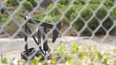 Endüstriyel şehir manzarası. La Brea Inglewood, Los Angeles 'ta. Çitin arkasında Jack 'i pompala. Sondaj kulesi ham petrol çıkarıyor. Çalışan pistonlu bir yağ makinası. Petrol ve doğalgaz endüstrisi