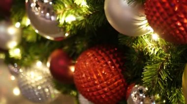 Neşeli Açık Hava Noel Ağacı 'nın yakın çekimleri. Peri arka planında parlak kırmızı toplar var. Odaklanmamış çelenk ışıkları, Bokeh etkisi. Mutlu Noeller ve Mutlu Noeller konsepti.