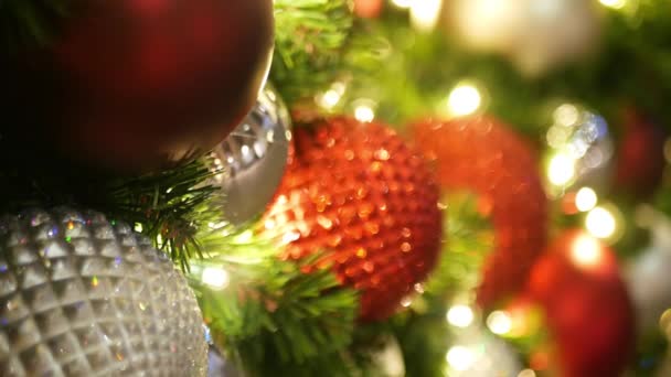 Primer plano del árbol de Navidad al aire libre decorado festivamente con bolas de color rojo brillante sobre el fondo borroso brillante hada. Luces de guirnalda desenfocadas, efecto Bokeh. Feliz Navidad y Felices Fiestas concepto. — Vídeos de Stock