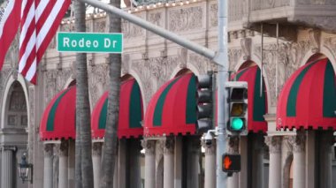 Beverly Hills 'te Amerika Birleşik Devletleri bayrağına karşı dünyaca ünlü Rodeo Drive Street tabelası. Los Angeles, Kaliforniya, ABD. Zengin zengin yaşam tüketiciliği, lüks markalar, yüksek sınıf mağazalar konsepti.