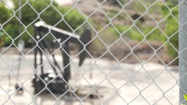Endüstriyel şehir manzarası. La Brea Inglewood, Los Angeles 'ta. Çitin arkasında Jack 'i pompala. Sondaj kulesi ham petrol çıkarıyor. Çalışan pistonlu bir yağ makinası. Petrol ve doğalgaz endüstrisi