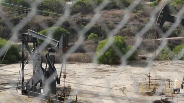 Paysage urbain industriel. La Brea Inglewood à Los Angeles. Prise de pompe de puits fonctionnant derrière la clôture. Extrait de forage de pétrole brut. Machine d'extraction d'huile avec piston de travail. Industrie pétrolière et gazière — Video