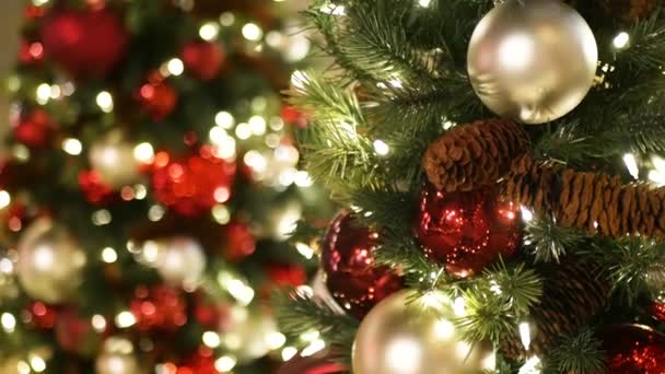お祭り騒ぎの閉鎖ぼやけた輝く妖精の背景に明るい赤いボールを持つ屋外クリスマスツリー。ガーランドライトを使用しないと、ボケ効果。メリークリスマスとハッピーホリデーのコンセプト. — ストック動画